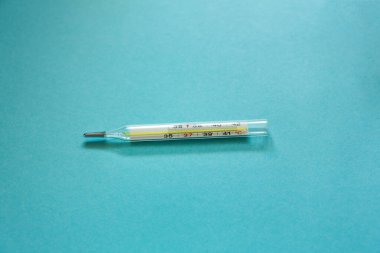 Mavi arka planda cıva termometresi. İlaçlar. Makro fotoğrafçılık, yumuşak odak.