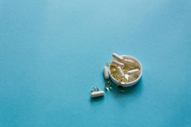 Tabletler, kapsüller, balık yağı. Uyuşturucuyla tedavi. Mavi arka planda ilaçlar. Makro fotoğrafçılık, yumuşak odak.