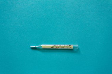 Mavi arka planda cıva termometresi. İlaçlar. Makro fotoğrafçılık, yumuşak odak.