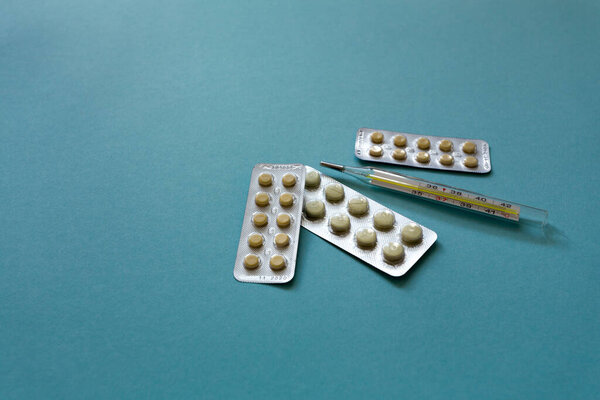 Лечение лекарствами. Лекарства, термометр на синем фоне. Макрофотография, мягкий фокус.