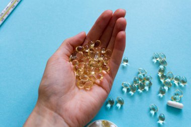 Uyuşturucuyla tedavi. Mavi arka planda el kapsülleri. Termometre. İlaçlar. Makro fotoğrafçılık, yumuşak odak.