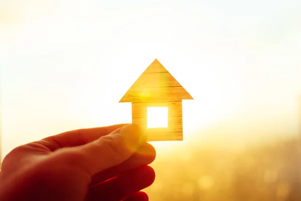 Man holding paper house isolated on the sunset sky