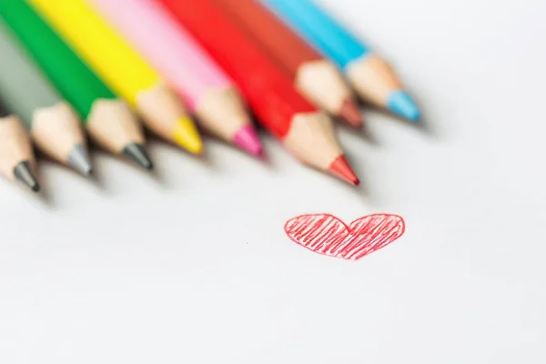 Hand Drawn Doodle Red Heart Photograph of Row of Multicolored Pencils on White Background. Valentine Mother\'s Day Kids Charity Romantic Love. Greeting Card Banner Poster. Selective Focus