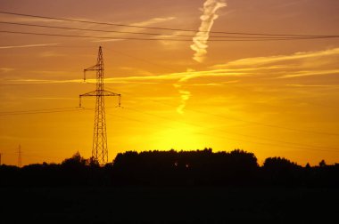 Elektrik Kulesi silueti günbatımı üzerinde. Yüksek gerilim enerji hatta turuncu gökyüzü.