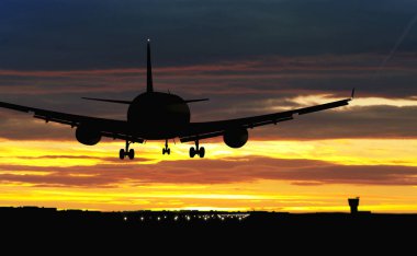 Günbatımı gökyüzü arka planda iniş sırasında uçak siluet. Jet uçak varış Havaalanı.