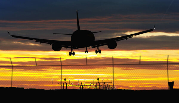 Silhouette airplane during landing on sunset sky in background. Jet plane arrival on airport.