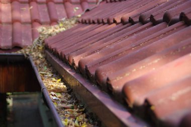 Clogged gutter through the leaves. Spring and autumn cleaning of the roof gutter. clipart