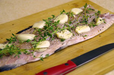 Taze çiğ balık pişirme için hazır. Alabalık otlar, sarımsak ve baharat ahşap oyun tahtası ile