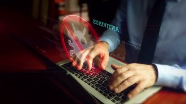 Kravatlı adam klavye üzerinde antivirüs hologram ekran ile dizüstü bilgisayarda yazıyor. Bilgisayar koruması, siber güvenlik ve internet güvenliği kavramı. Doğal el kamera sallamak.