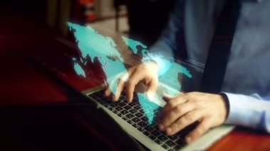Bilgisayar korsanı klavye üzerinde dünya haritası hologramı ile dizüstü bilgisayarda yazma. Fütüristik küreselleşme kavramı, dünya çapında ağ, uluslararası iş ve sosyal medya bağlantısı. El kamera sallamak.