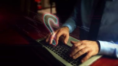 Klavyenin üzerinde soru işaretli kalp hologramı ekranı olan bir adam dizüstü bilgisayarda yazıyor. Bilgi, faq, bilgi arama ve eğitim konsepti. Doğal el kamerası sallaması..
