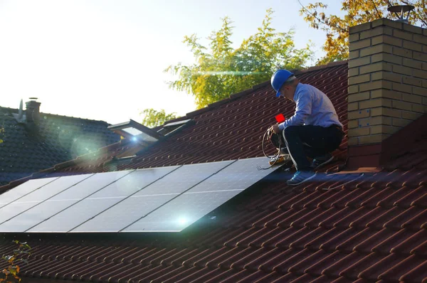 Teknisyen çatıya güneş panelleri kuruyor.