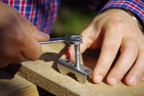 A carpenter with a metal wrench in hand tightens the screw. Home hobby and DIY.