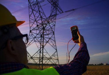 Güç hattı altyapı denetimi sırasında gösterge aletli bir mühendis. İncelemedeki elektrikçi. Enerji ağının ölçümü.
