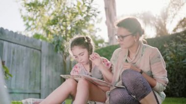 Mutlu gülümseyerek anne ve çocuk eğlenmek ve çizim resimleri açık havada yaz MIDL bahçesinde vurdu