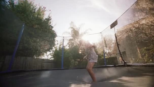 Ragazza che salta su un trampolino sotto il sole. rallentatore — Video Stock