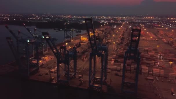 Воздушный дрон. Полет вокруг крана в контейнерном порту с кораблями и кранами ночью — стоковое видео