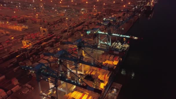 Повітряний дрон. Політ над контейнерним портом з кораблями і кранами вночі — стокове відео
