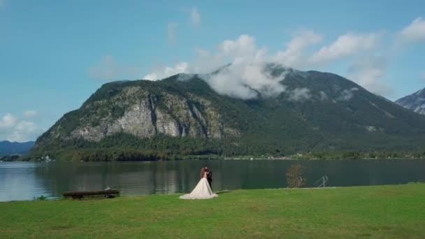 Hochzeitstag. Frischvermählte stehen zusammen in der Nähe des malerischen blauen Sees und Berges — Stockvideo