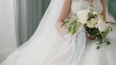 Beyaz gelinlik giymiş gelinin elinde güzel gelin buketi.