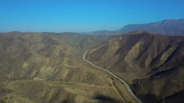 Aerial drone over countryside and long winding road whit blue sky, California, EE.UU. — Vídeos de Stock