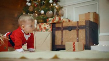 Bir hediye baktı inanılmaz şirin küçük erkek veya kız yürümek ve oyun heyecanlı. bir şekilde dekore edilmiş Noel ağacı ve Hediyelik gülümse. Orta vurdu