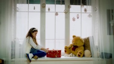 Küçük kız camda oturur ve hediye alır ve o açık son derece mutlu Noel o mevcut.