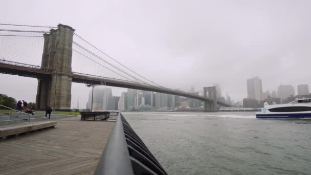 Небоскрёбы Манхэттена и Бруклинского моста, Нью-Йорк. туман над небоскребами, облачная погода и движение на реке — стоковое видео