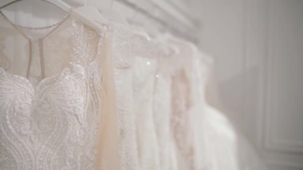 Ljusa dyrbara vitt bröllopsklänningar hängande i en bridal shop. — Stockvideo