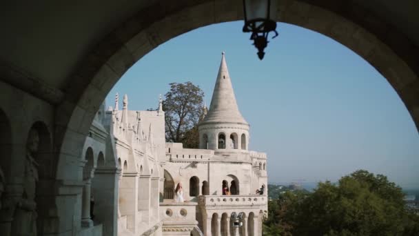 Una joven muy hermosa o novia en un vestido blanco, permanecer en el balcón del antiguo castillo, y mira a la ciudad de Budapest — Vídeo de stock