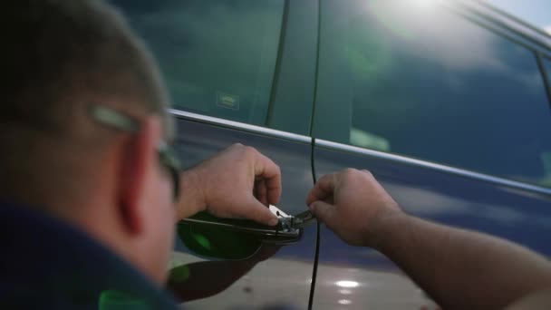 Masculino mecânico ou ladrão segurando Lockpicker para abrir a porta do carro — Vídeo de Stock