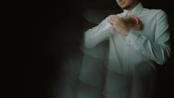 Homme boutonne sa chemise blanche debout devant une fenêtre lumineuse, entreprise, concept de mode et de vêtements - gros plan — Video