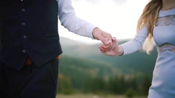 Pareja cogida de la mano caminando hacia el atardecer. romántico en el amor al atardecer de montaña. De cerca. — Vídeo de stock