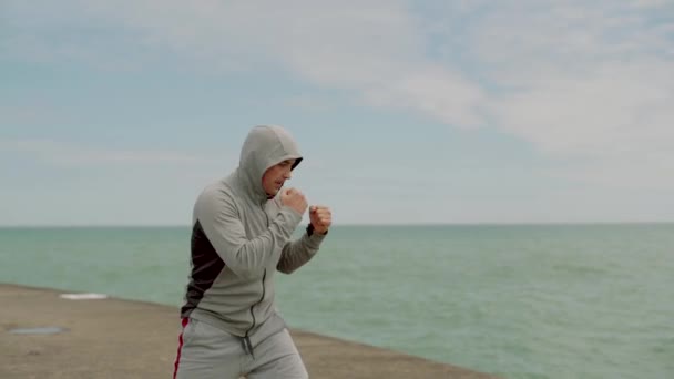 Молодий спортсмен, активно займається спортом, кросфітом, боксом, кікбоксингом на березі озера — стокове відео