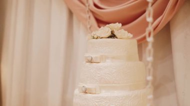 Düğün pastası, gül ile dekore edilmiş ahşap bir masa üzerinde duruyor. Yakın çekim