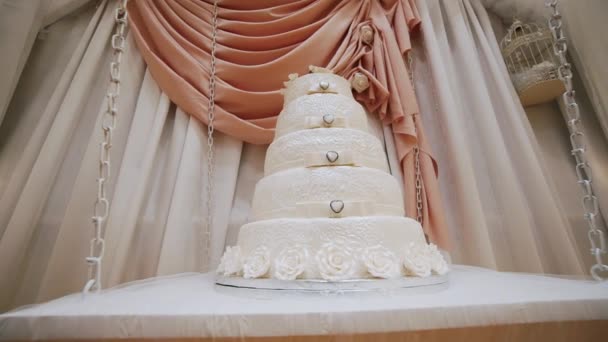 La torta nuziale, decorata con rose, si erge su un tavolo di legno. Chiudete. fotocamera diapositiva — Video Stock