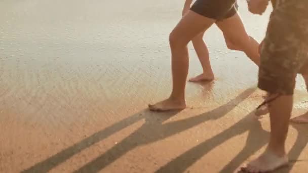 Beine einer kaukasischen Familie, die barfuß am Strand und auf den Wellen läuft — Stockvideo