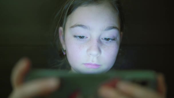 Nacht shot van kinderen tiener meisje gezicht browsen Tablet PC of smartphone met lichtreflectie op. Close-up — Stockvideo