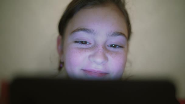 Plan de nuit des enfants adolescent fille visage navigation tablette PC avec réflexion de la lumière sur elle et sourire — Video