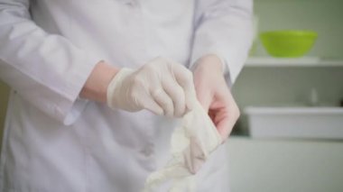 Yakın çekim doktorlar ellerini gösterir. O ellerini beyaz tek kullanımlık eldiven koyar