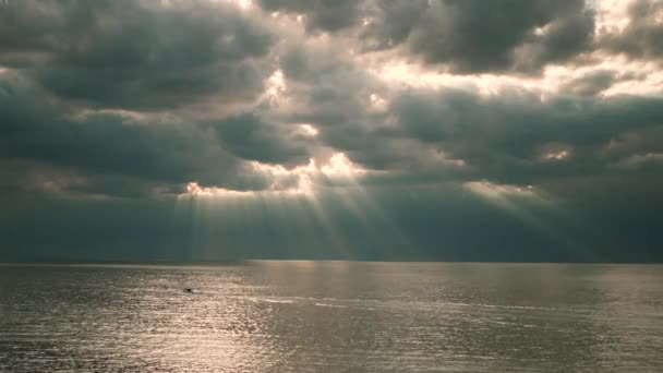 Прекрасні промені сонця, що пробиваються крізь хмари над водою море або велике озеро і човен — стокове відео