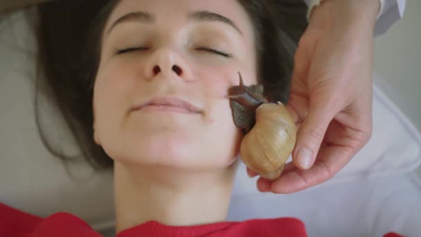 Jovem mulher no spa recebe uma massagem facial com caracóis Achatina. Os caracóis comem pele morta dos produzidos. No final, deixa a pele lisa e fresca. Tiro médio — Vídeo de Stock