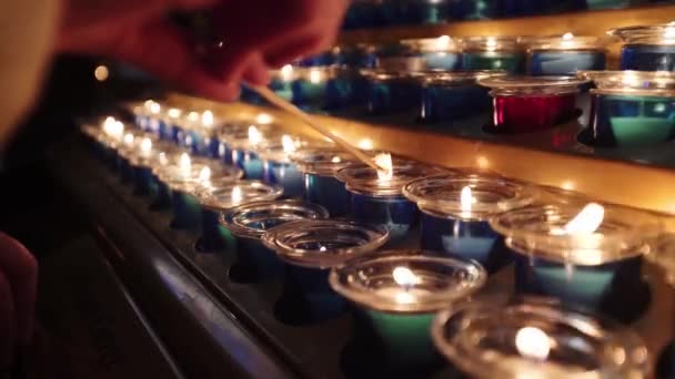 Frau zündet Kerze zwischen anderen Kerzen an — Stockvideo