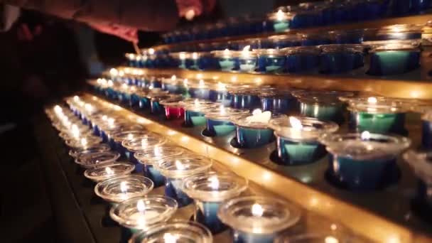 Small candles in church. rows of burning candles in a dim church. small firing candles in catholic church on dark background, close up — Stock Video