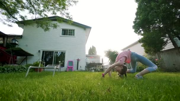 El niño se dedica a las acrobacias al atardecer en el patio trasero. jugar juego. Movimiento lento — Vídeo de stock