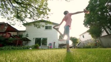 Çocuk arka bahçede gün batımında akrobasi ile meşgul. Yavaş çekim. kamerayı hareket ettir
