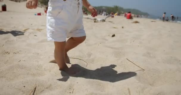 Piernas de bebé irreconocible caminando en la playa de arena. En cámara lenta. Primer plano — Vídeos de Stock