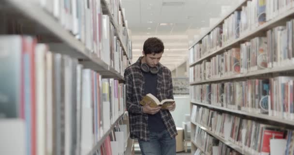 Studente universitario in piedi sul pavimento in biblioteca, libro di lettura. Midle shot — Video Stock