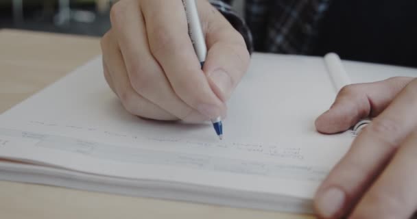 Ο άνθρωπος γράφει σημειώσεις στο σημειωματάριο. Κοντινό. Έκδοση 1 — Αρχείο Βίντεο