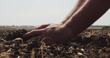 Çiftçi elleri toprak bir avuç tutar ve güneşli bir günde sahada parmaklarını n içinden geri döker. Yan görüş Yavaş hareket Ver 7'yi kapat